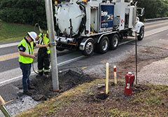 Men using hydro excavator to dig alongside a road.